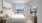 Staged bedroom with neutral accents,  sunlit windows, and carpet flooring