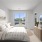 Staged bedroom with neutral accents,  sunlit windows, and carpet flooring