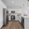 Kitchen with quartz island, white backsplash, stainless steel appliances, and white cabinetry