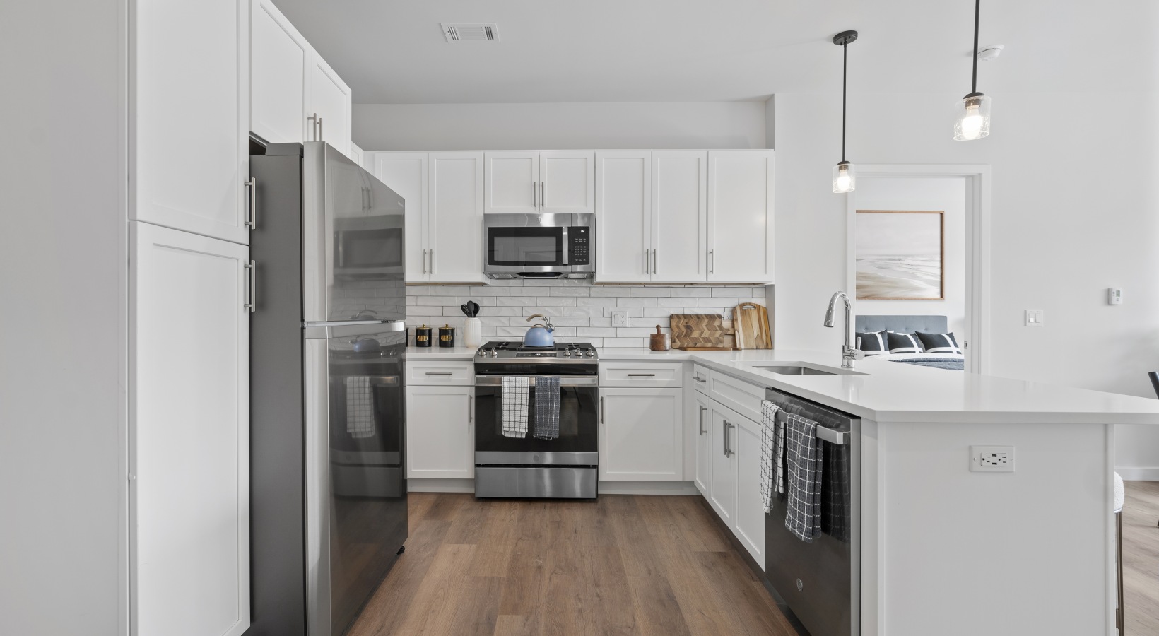 Luxury 1 & 2 Bedroom Apartments at Riverside Wilton Kitchen with quartz island, white backsplash, stainless steel appliances, and white cabinetry